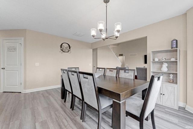 dining space with baseboards, light wood-style flooring, visible vents, and an inviting chandelier