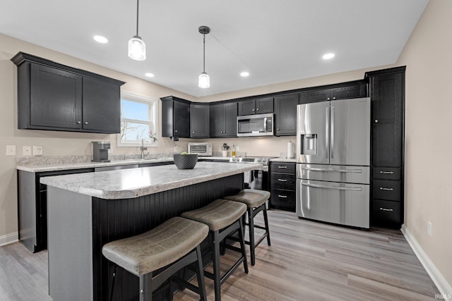kitchen with light countertops, appliances with stainless steel finishes, a breakfast bar area, and dark cabinets