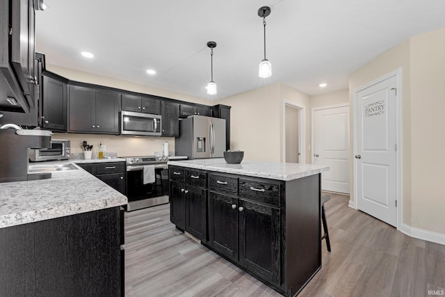 kitchen featuring light countertops, appliances with stainless steel finishes, dark cabinetry, and light wood-style floors