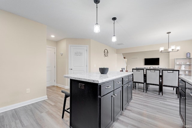 kitchen with light wood-style flooring, decorative light fixtures, light countertops, and dark cabinets