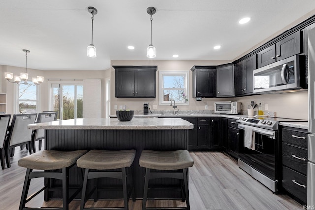 kitchen featuring dark cabinets, a kitchen island, a kitchen breakfast bar, and appliances with stainless steel finishes