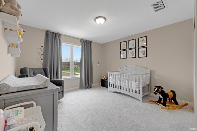 carpeted bedroom featuring baseboards, visible vents, and a crib