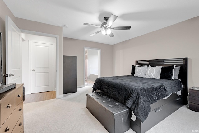 bedroom featuring light colored carpet, ceiling fan, ensuite bathroom, and baseboards
