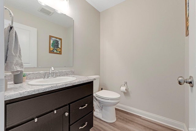 bathroom featuring vanity, baseboards, toilet, visible vents, and wood finished floors