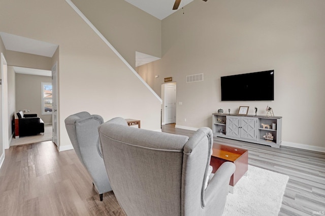 living room featuring light wood-style floors, ceiling fan, baseboards, and visible vents