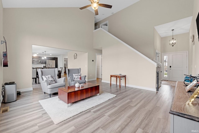 living room featuring high vaulted ceiling, light wood-type flooring, baseboards, and ceiling fan