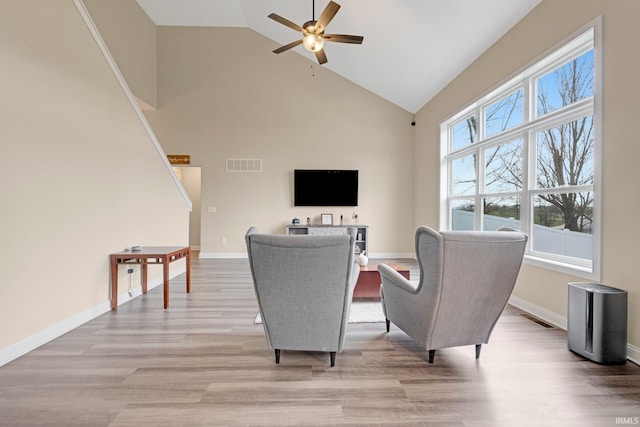 living room with light wood-type flooring, high vaulted ceiling, a ceiling fan, and visible vents