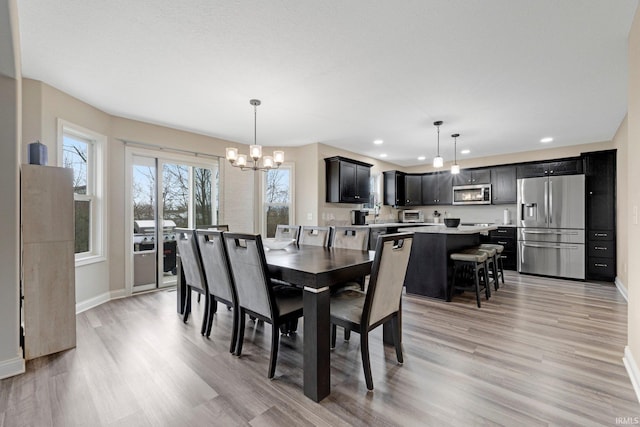 dining area with a notable chandelier, baseboards, recessed lighting, a toaster, and light wood-style floors