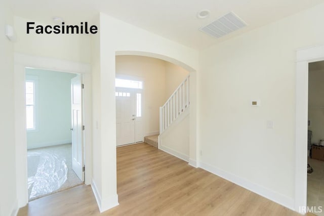 entryway featuring arched walkways, a healthy amount of sunlight, visible vents, and light wood-style floors