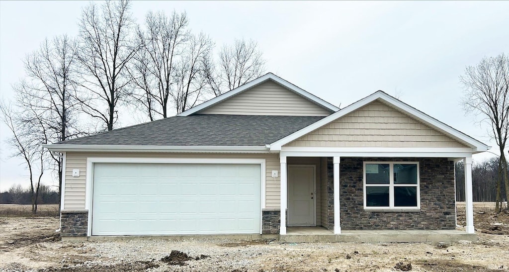 view of front of home with an attached garage, roof with shingles, stone siding, and a porch