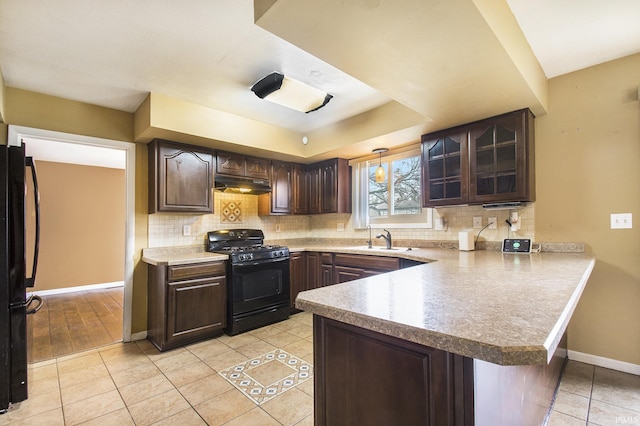 51821 Trowbridge Ln, South Bend, IN 46637 - kitchen with a peninsula, a sink, dark brown cabinetry, under cabinet range hood, and black appliances