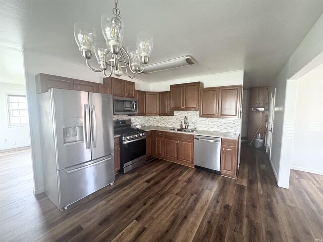 kitchen with stainless steel appliances, dark wood-type flooring, a notable chandelier, and a sink