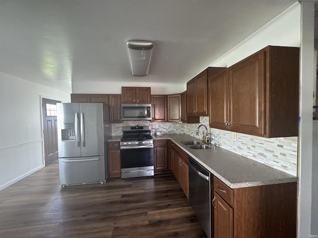 kitchen with dark wood-type flooring, decorative backsplash, a sink, and appliances with stainless steel finishes