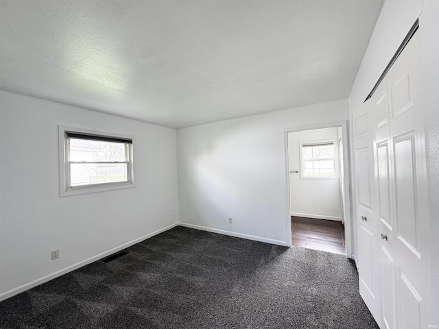 empty room featuring dark carpet and baseboards