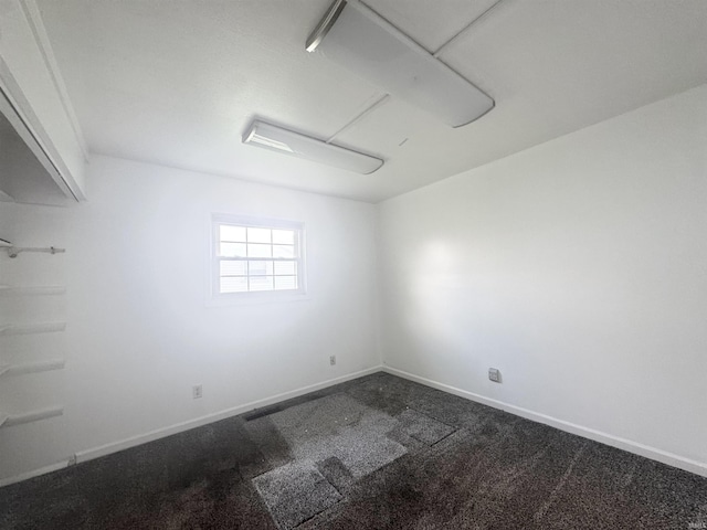 unfurnished room featuring dark colored carpet and baseboards
