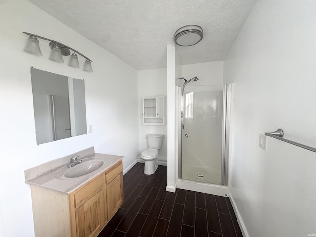 full bathroom with a shower stall, baseboards, a textured ceiling, and toilet