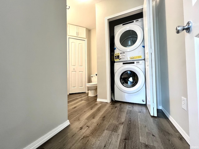 laundry area with stacked washer and dryer, baseboards, laundry area, and dark wood-style floors