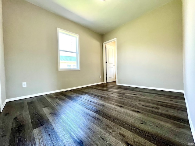 spare room with dark wood-style flooring and baseboards