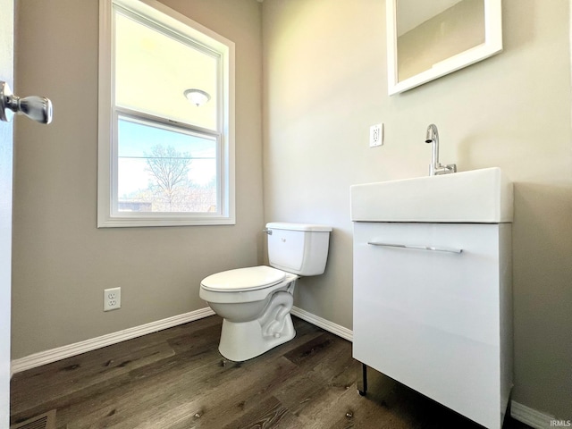 bathroom featuring visible vents, toilet, wood finished floors, a sink, and baseboards