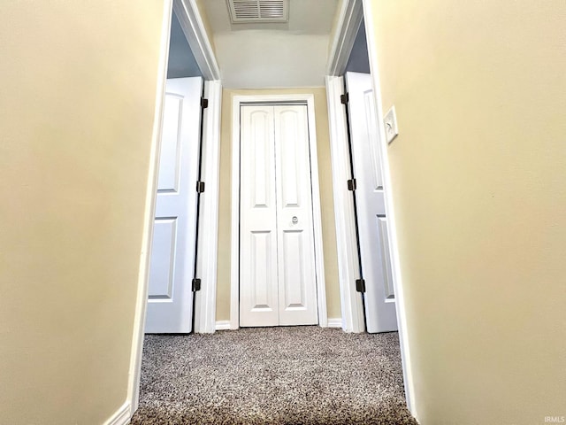 hallway with baseboards, carpet, and visible vents