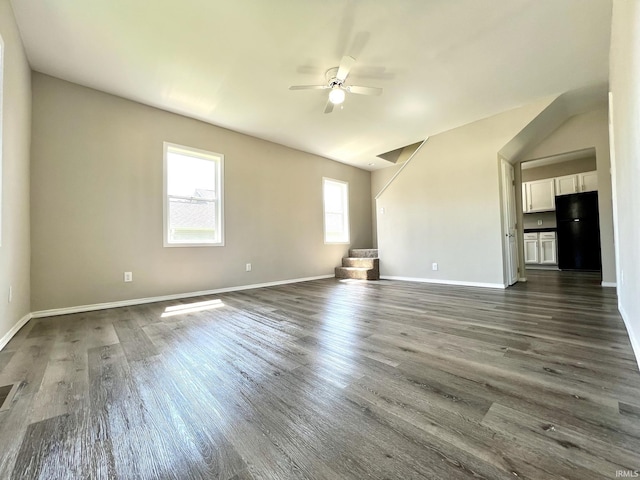 unfurnished living room with dark wood-style floors, baseboards, vaulted ceiling, and ceiling fan