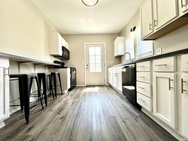 kitchen with white cabinets, stainless steel dishwasher, range with electric stovetop, and dark wood-style flooring