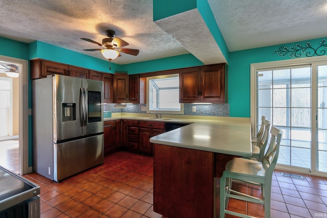 kitchen featuring range with electric stovetop, stainless steel fridge, a peninsula, and a textured ceiling