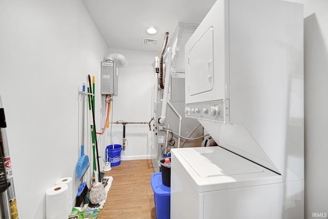617 Pearl St, Culver, IN 46511 - clothes washing area with visible vents, stacked washing maching and dryer, laundry area, wood finished floors, and water heater