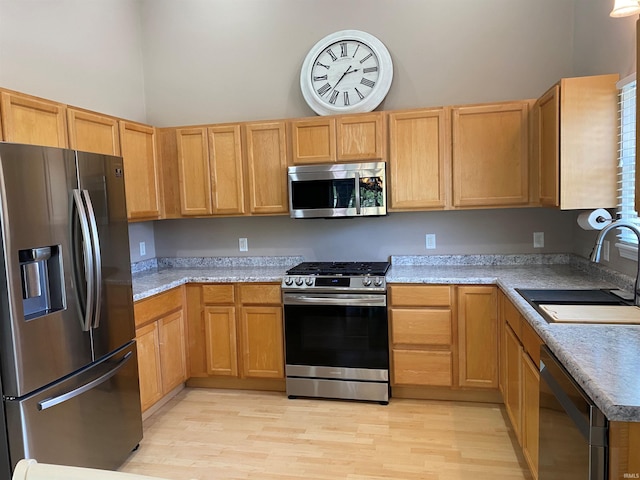 kitchen with a high ceiling, a sink, light countertops, light wood-style floors, and stainless steel appliances