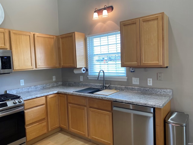 kitchen featuring a sink, light countertops, light wood-type flooring, appliances with stainless steel finishes, and light brown cabinetry