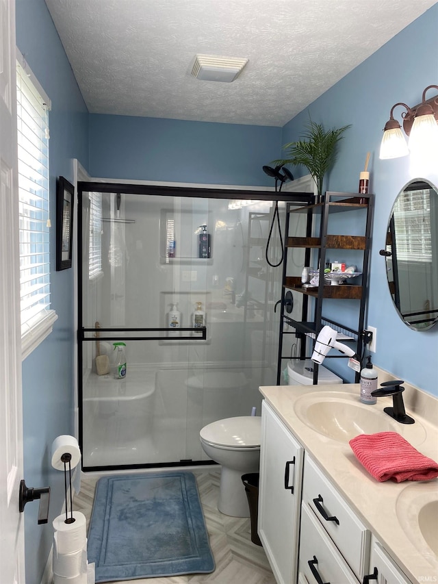 full bath with a shower stall, a textured ceiling, and a sink