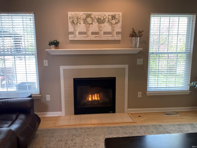interior details featuring wood finished floors, visible vents, a fireplace, and baseboards