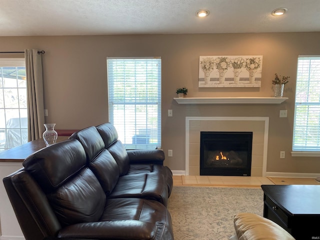 living area featuring a tiled fireplace, baseboards, and recessed lighting