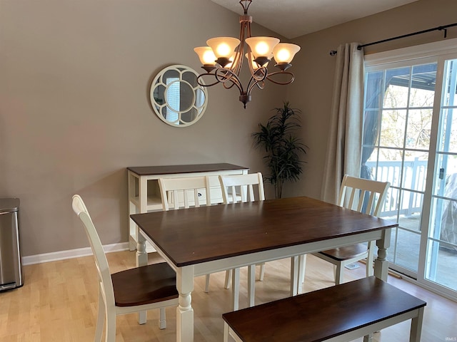 dining space with a chandelier, vaulted ceiling, light wood-type flooring, and baseboards