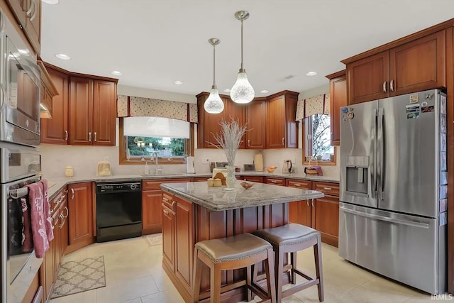 kitchen with stone countertops, recessed lighting, a center island, appliances with stainless steel finishes, and a sink