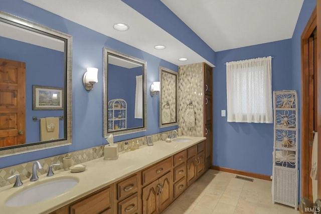 bathroom with double vanity, visible vents, baseboards, and a sink