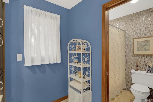 full bath featuring toilet, a shower with curtain, and baseboards