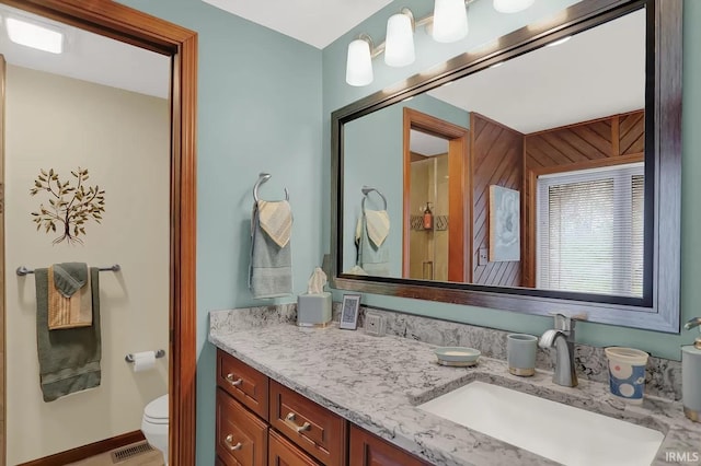 bathroom with toilet, vanity, and visible vents