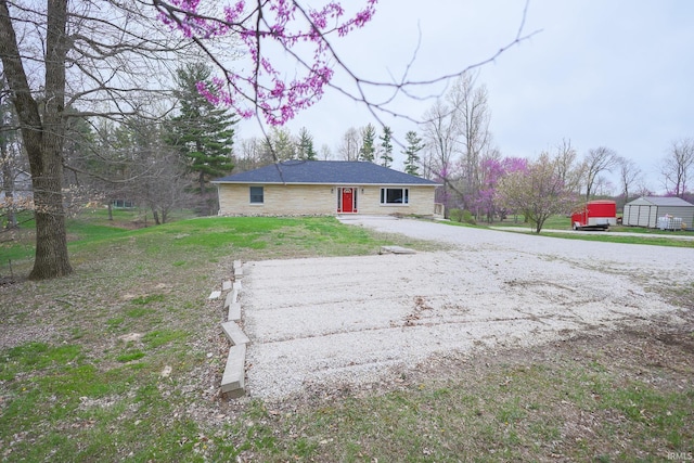 ranch-style home with gravel driveway and a front lawn