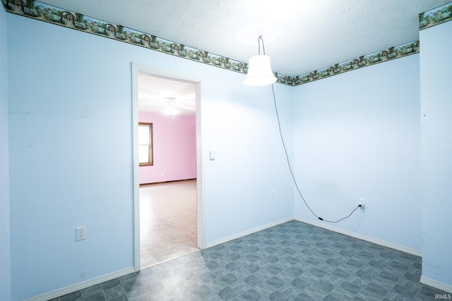 unfurnished room with a textured ceiling, baseboards, and tile patterned floors