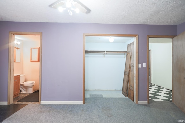 unfurnished bedroom featuring ceiling fan, connected bathroom, a closet, carpet floors, and baseboards