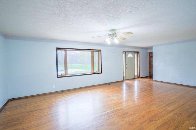 unfurnished living room featuring a textured ceiling, wood finished floors, baseboards, and a ceiling fan