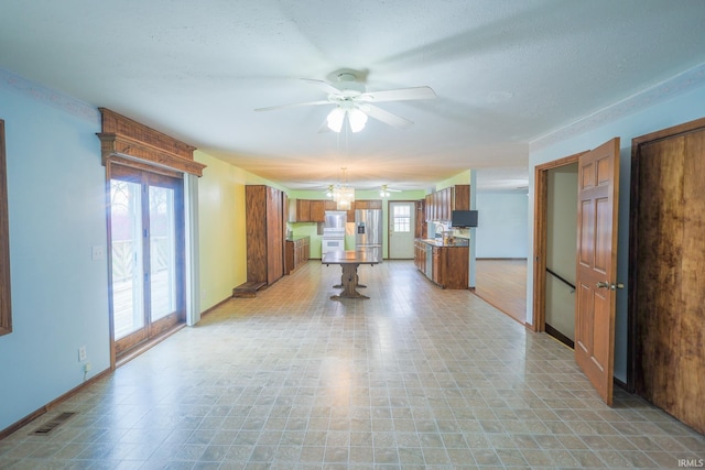 interior space featuring baseboards, stainless steel fridge, visible vents, brown cabinetry, and ceiling fan