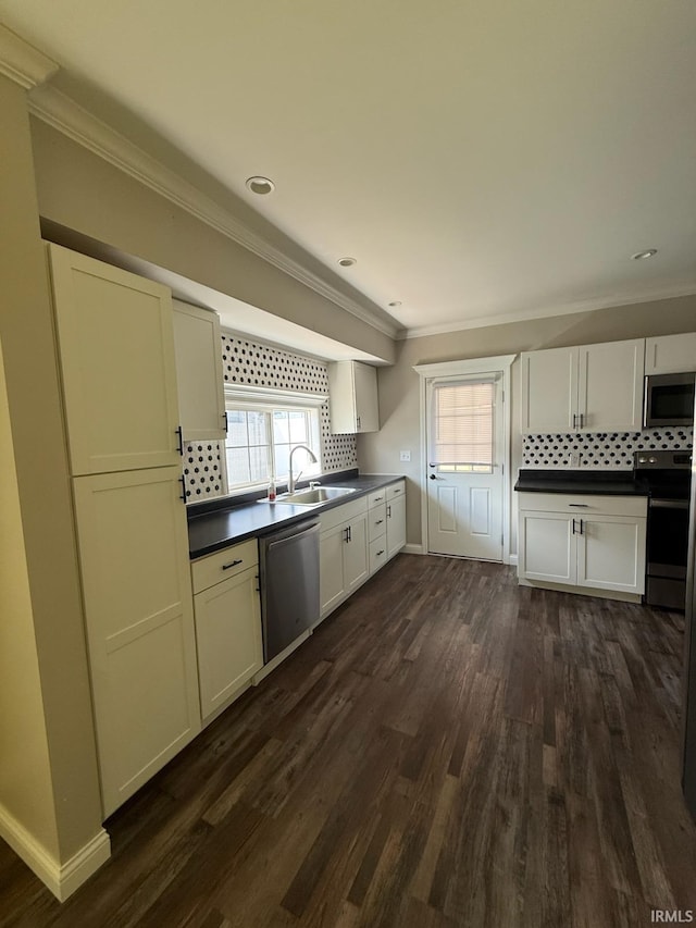 kitchen featuring crown molding, decorative backsplash, dark countertops, a sink, and stainless steel appliances