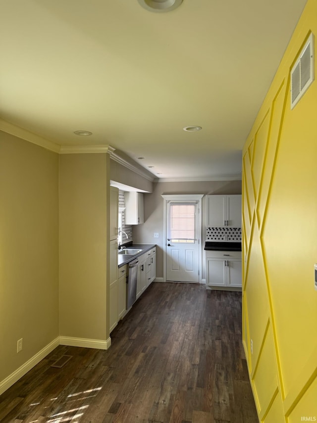 kitchen featuring stainless steel dishwasher, dark countertops, visible vents, and crown molding