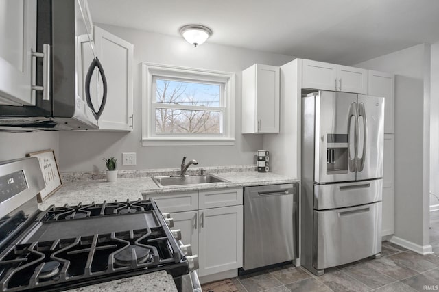 11314 NE Wawasee Dr, Syracuse, IN 46567 - kitchen featuring baseboards, a sink, white cabinetry, stainless steel appliances, and light stone counters