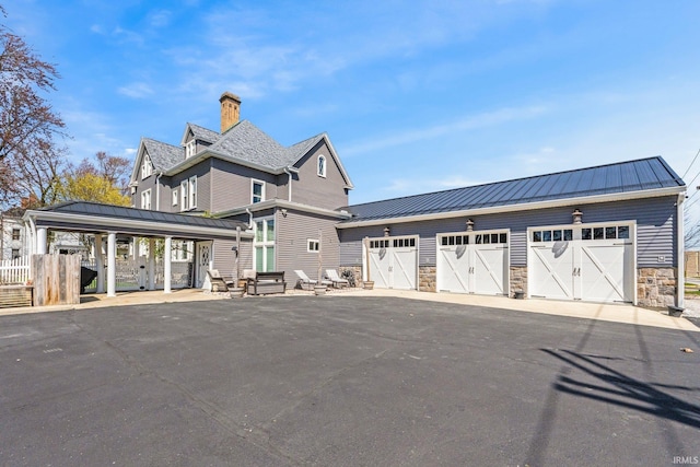328 W Market St, Bluffton, IN 46714 - view of front of home with an outdoor structure, stone siding, a standing seam roof, and metal roof