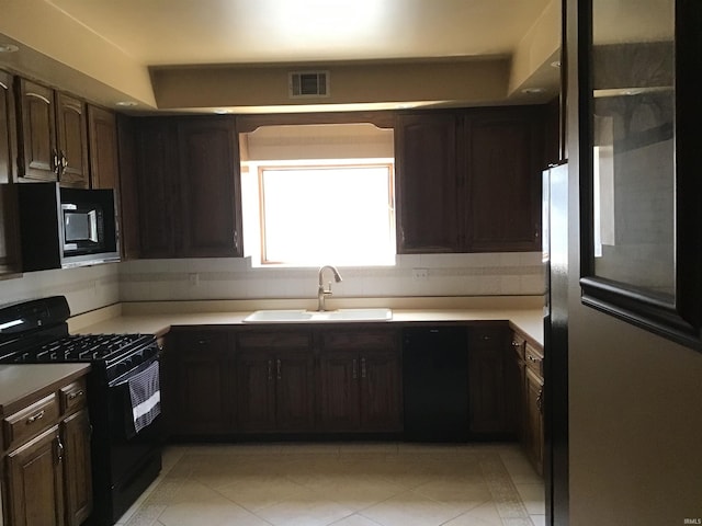 kitchen featuring tasteful backsplash, light tile patterned floors, visible vents, a sink, and black range with gas stovetop