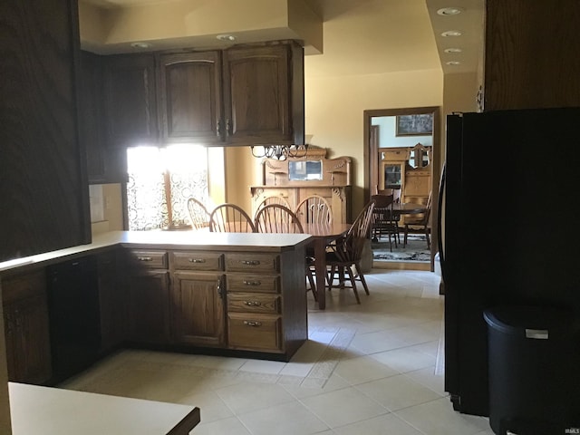 kitchen with light countertops, freestanding refrigerator, light tile patterned flooring, and a peninsula
