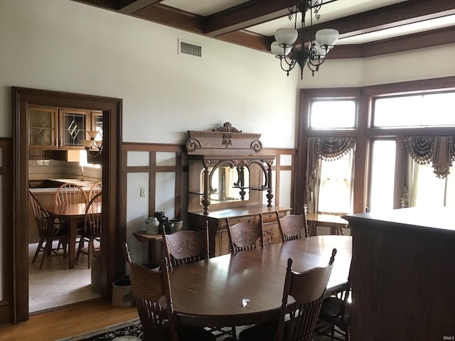 dining space featuring visible vents, beam ceiling, an inviting chandelier, and wood finished floors